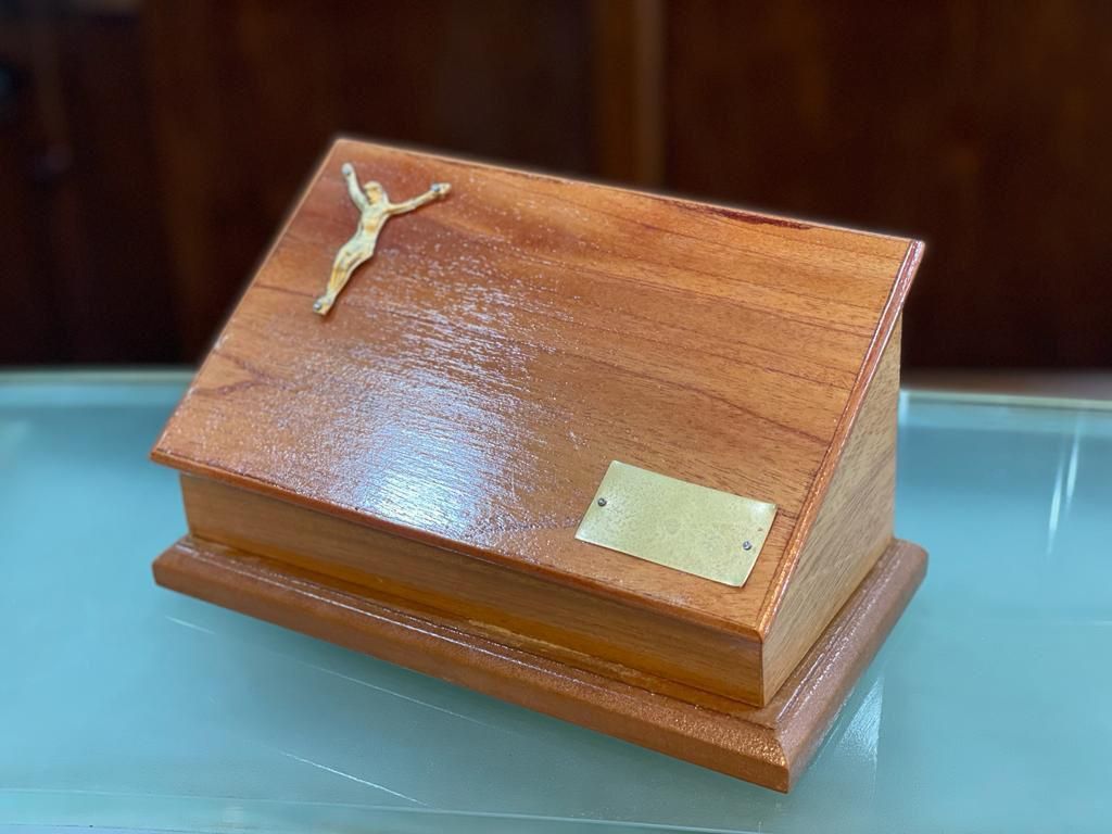 Una pequeña caja de madera con una cruz encima.