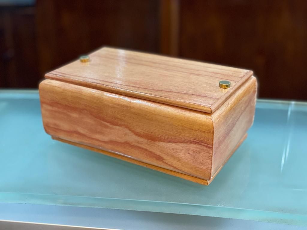 Una pequeña caja de madera está encima de una mesa de vidrio.