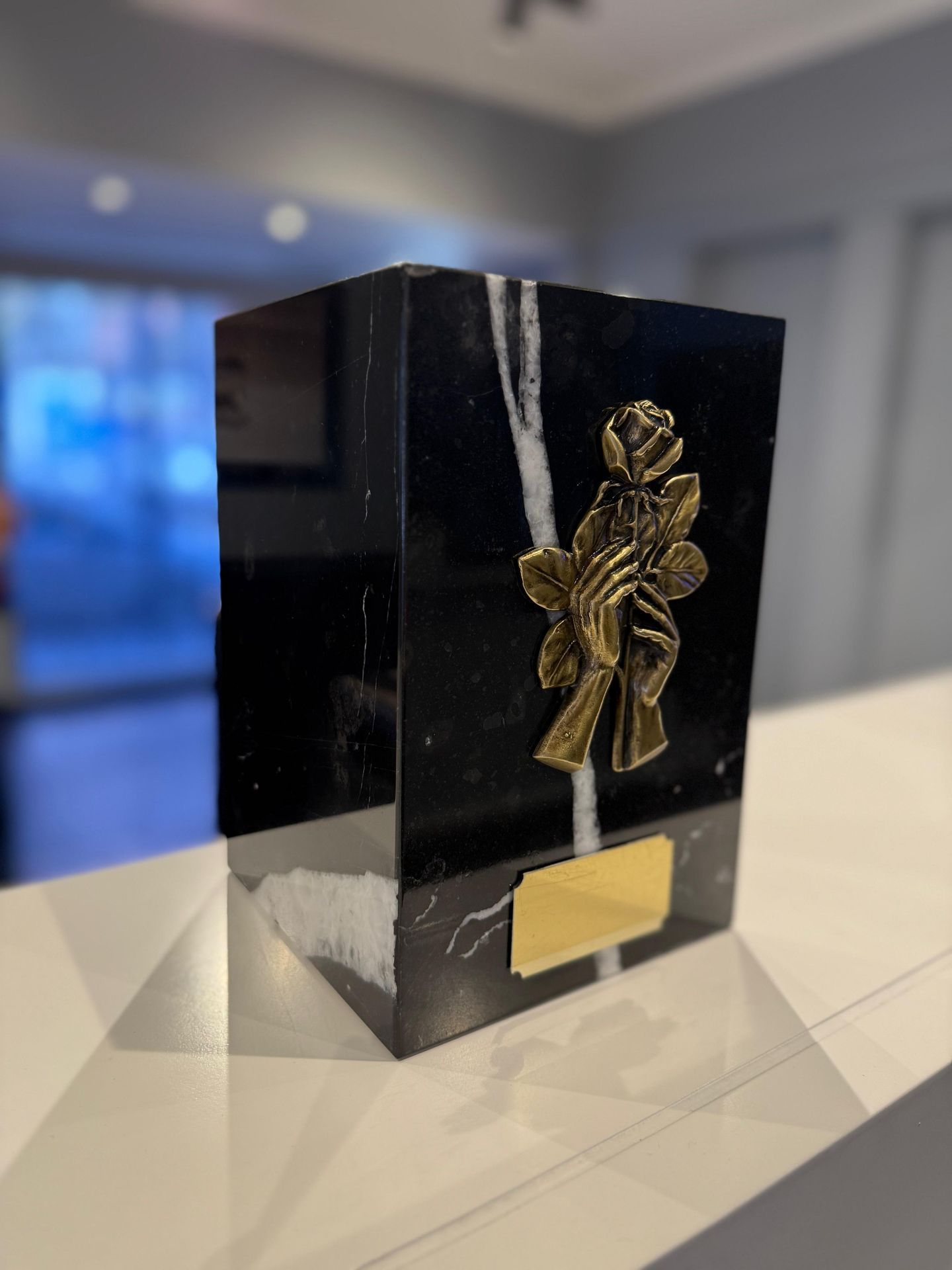 Una caja negra con una flor dorada encima.