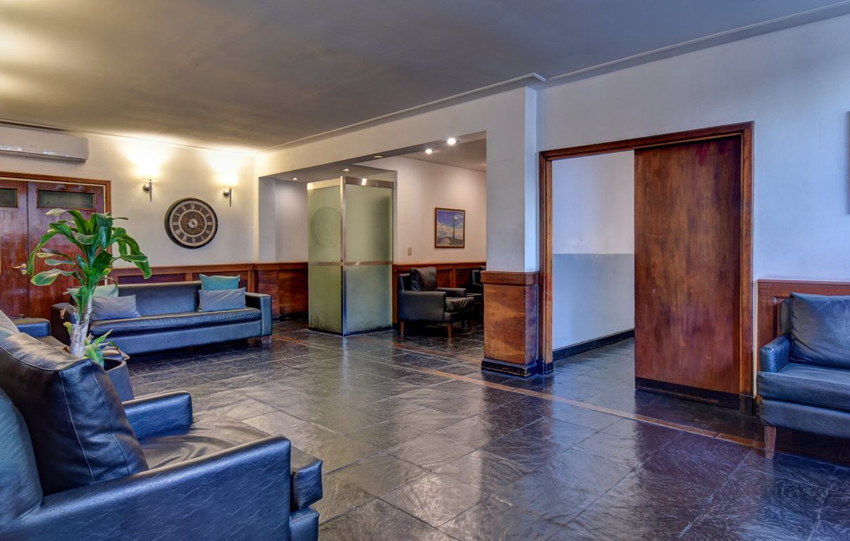 Una sala de estar con un sofá, sillas y una planta.