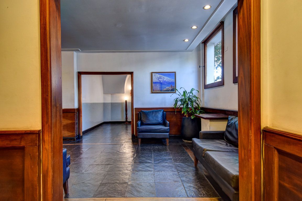 Un pasillo con un sofá, una silla y un cuadro en la pared.