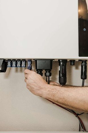 Twee mannen installeren zonnepanelen op het dak van een huis.