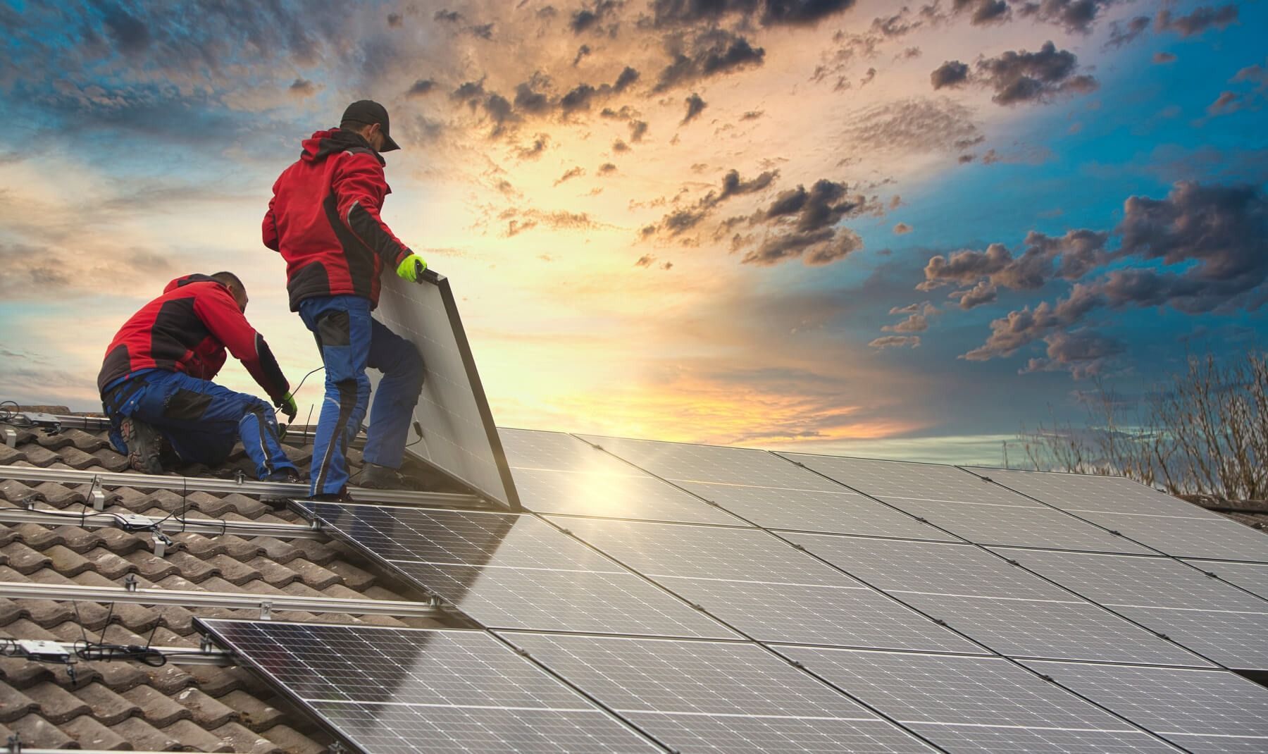 Twee mannen installeren zonnepanelen op het dak van een huis.