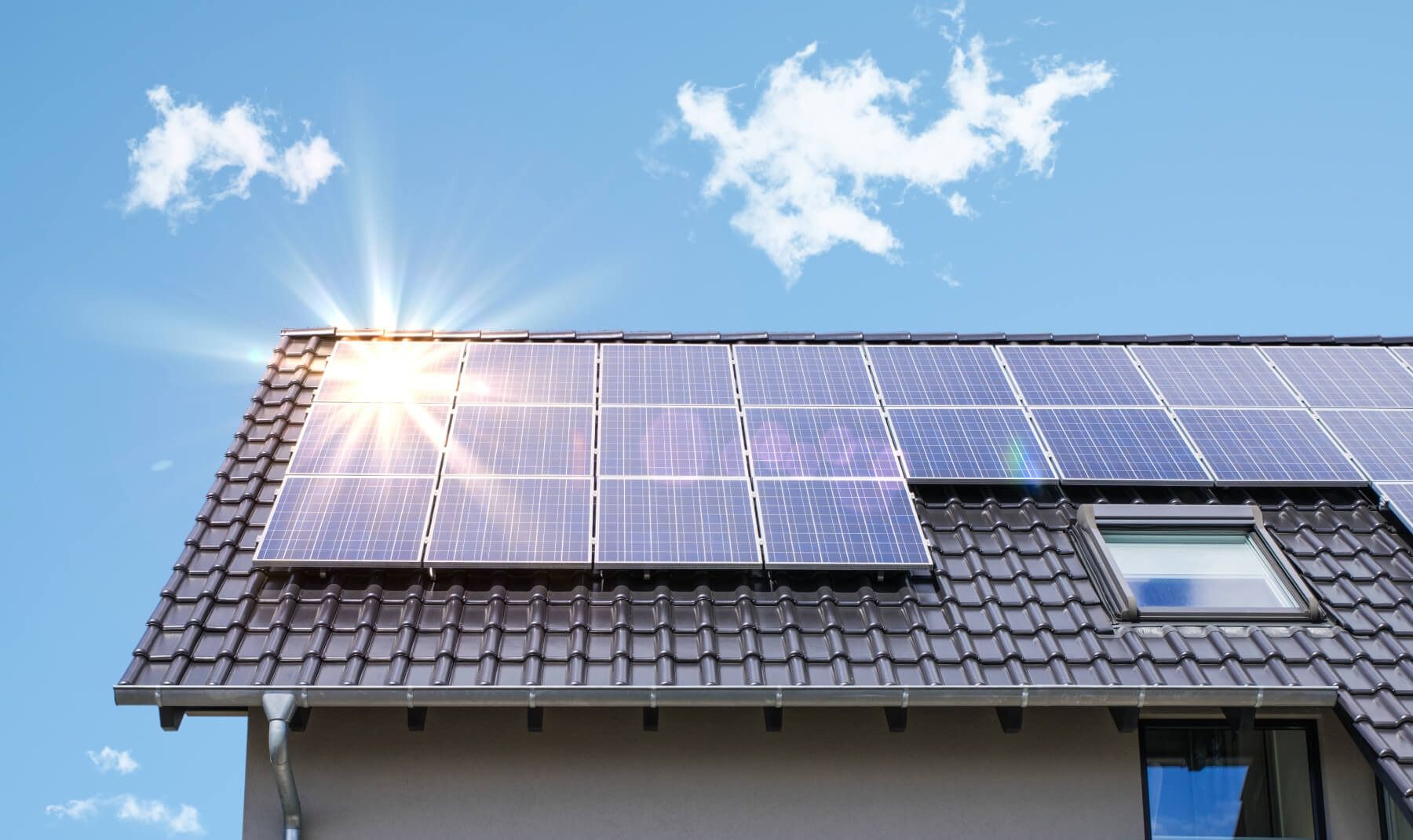 De zon schijnt door de zonnepanelen op het dak van een huis.