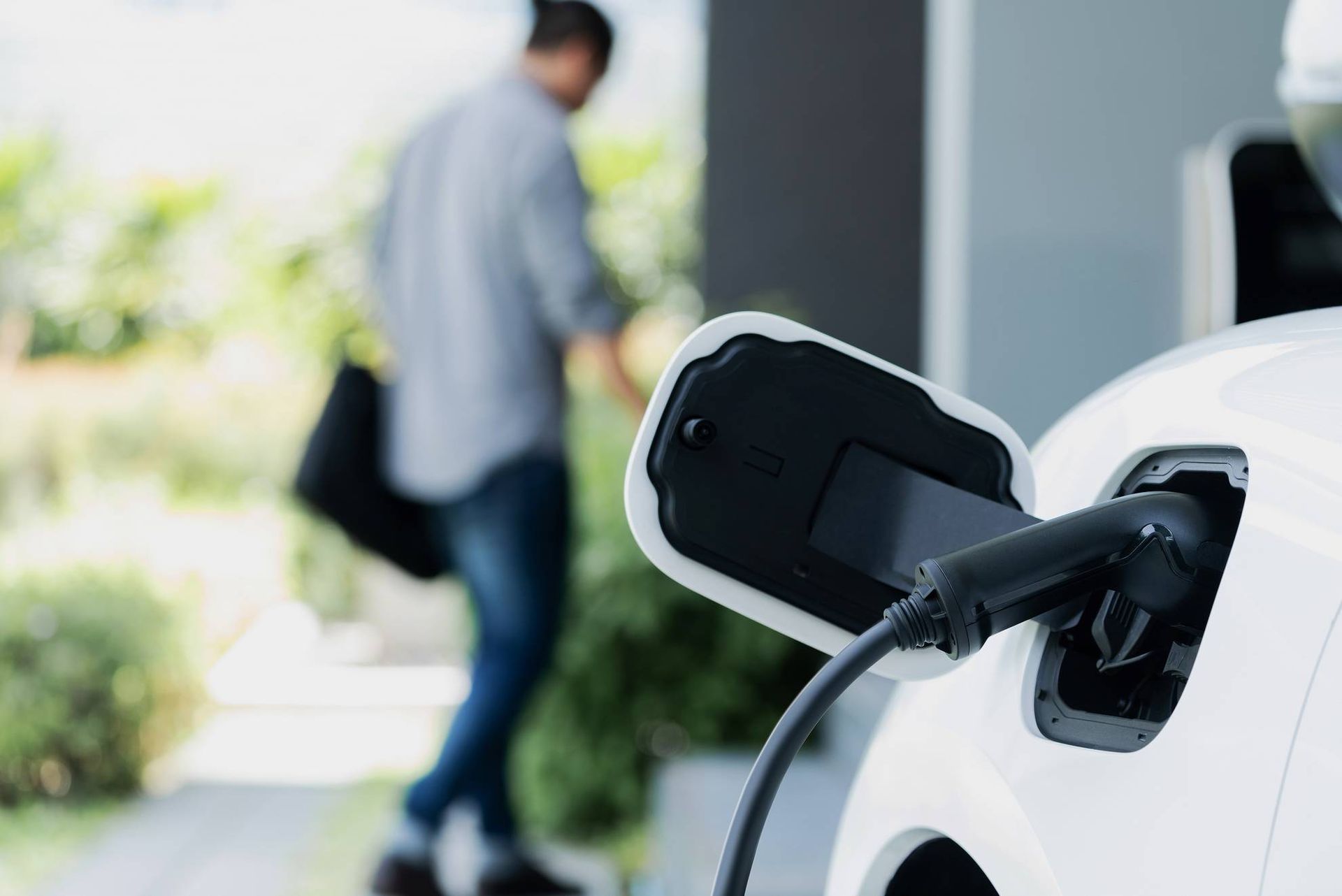 Een man laadt een elektrische auto op bij een laadstation.