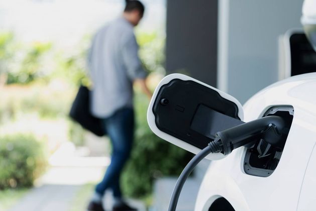 Een man laadt een elektrische auto op bij een laadstation.
