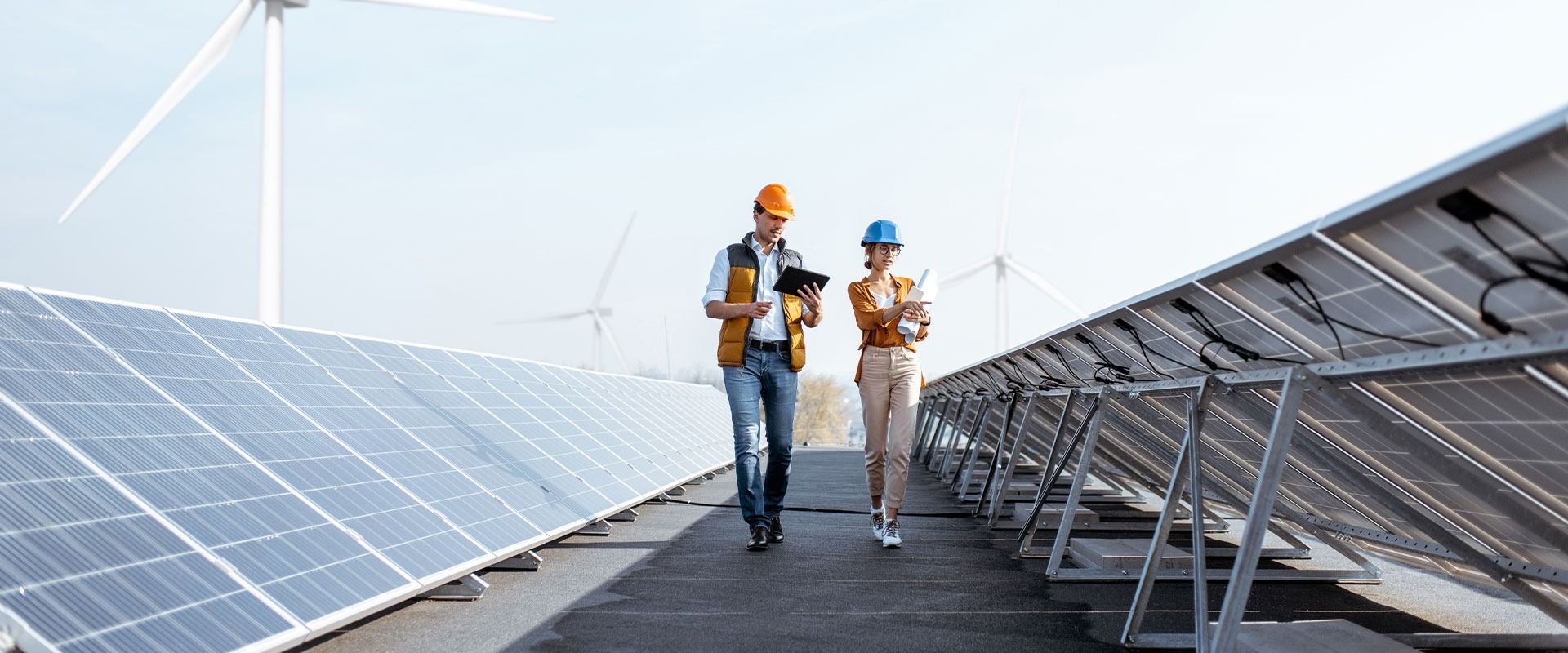 Een man en een vrouw lopen over een rij zonnepanelen.