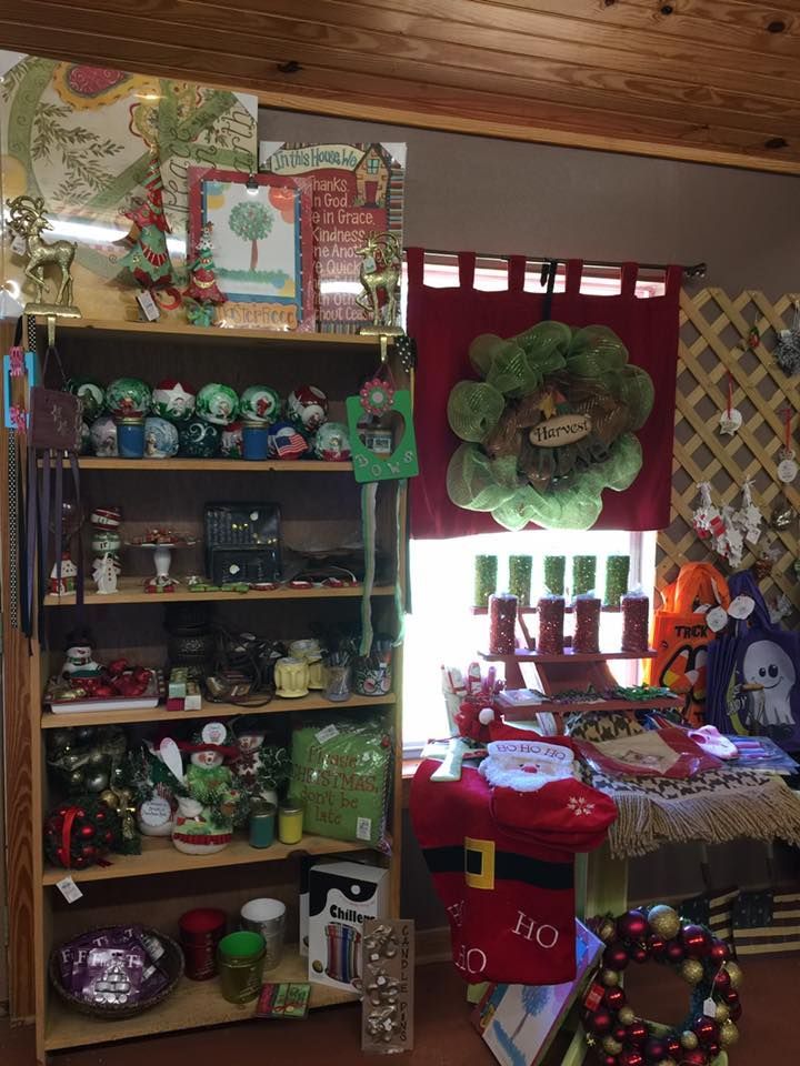 Shelves filled with Christmas-themed decor: ornaments, figurines, gift bags, and a wreath. A window with red curtains.