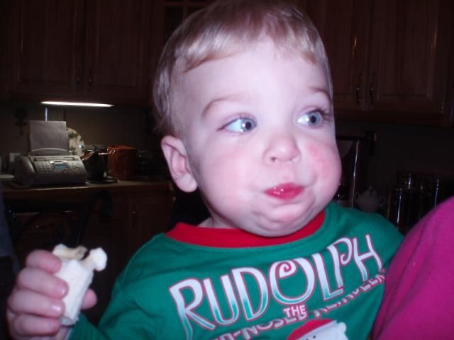 Blond toddler with cheeks puffed, wearing a 