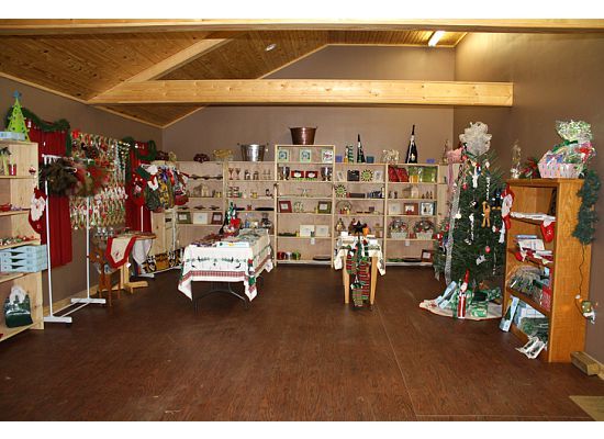 Interior of a gift shop with shelves of merchandise and Christmas decorations; brown flooring and ceiling.