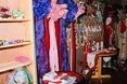 A person in a blue sequined robe, pink scarf, and a shop interior.