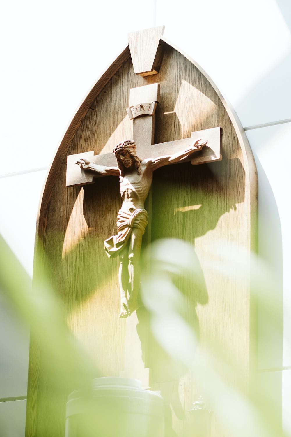 A statue of jesus on a cross is hanging on a wall.