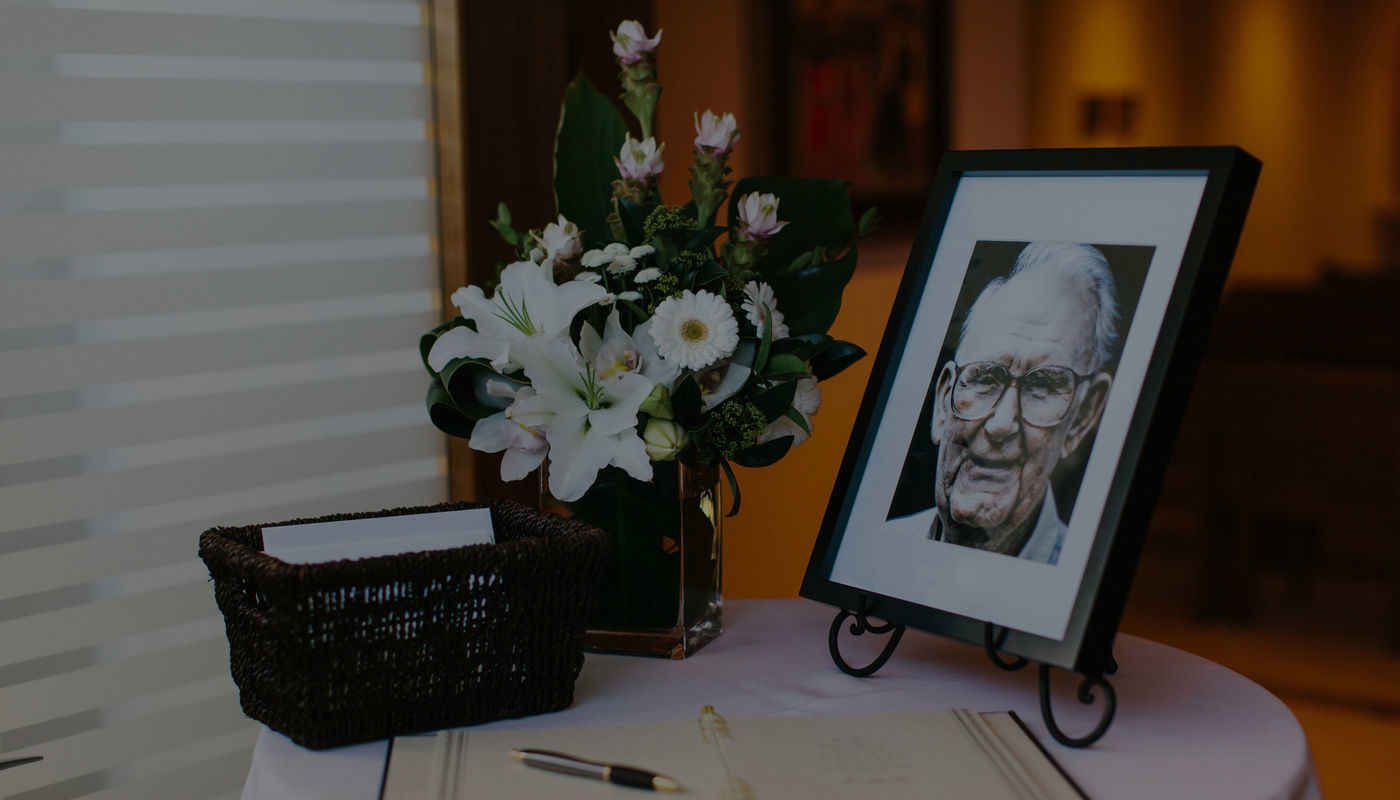 A picture of a man is on a table next to a vase of flowers.