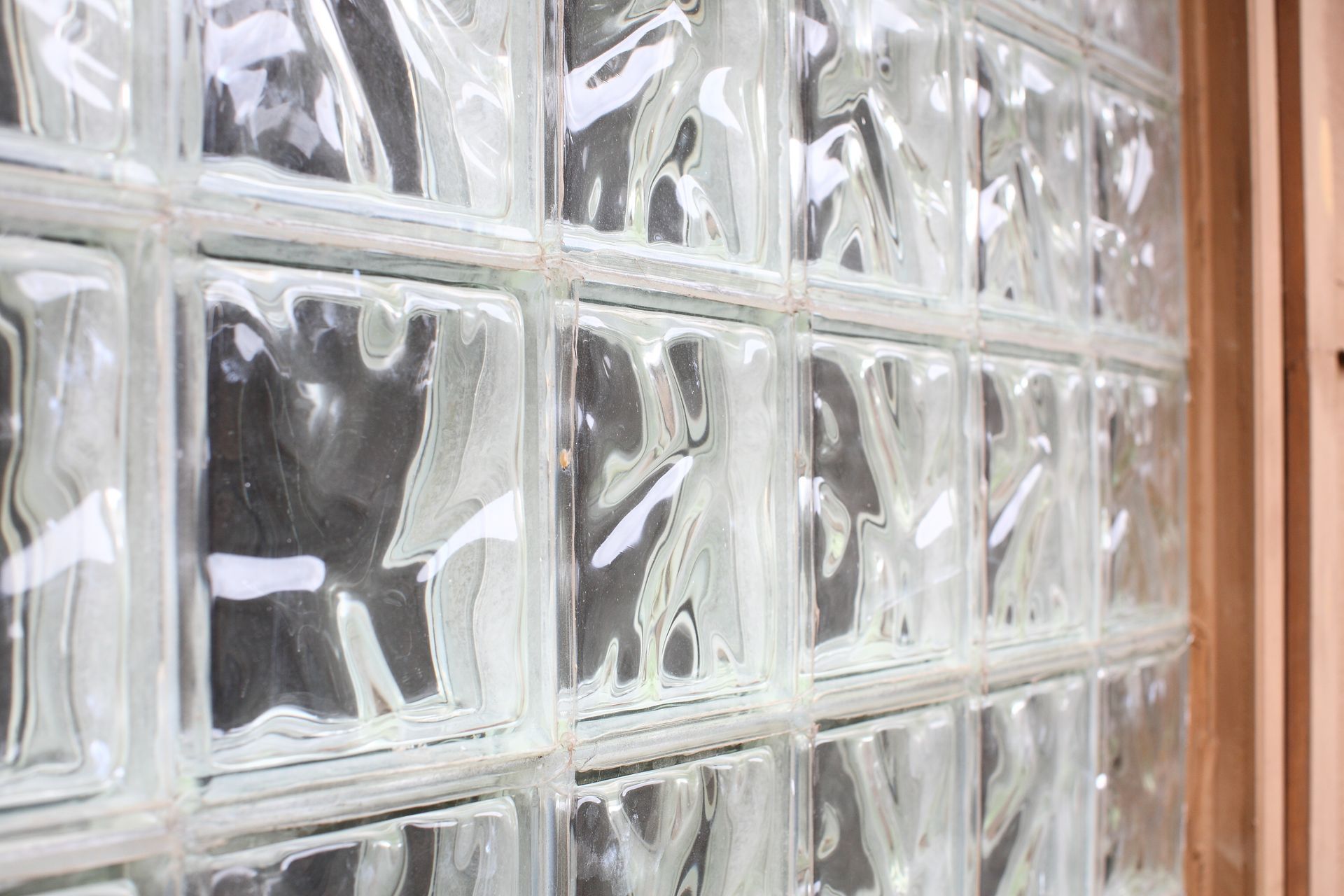 A close-up view of a wall made of translucent, wavy-patterned glass blocks set in a grid.