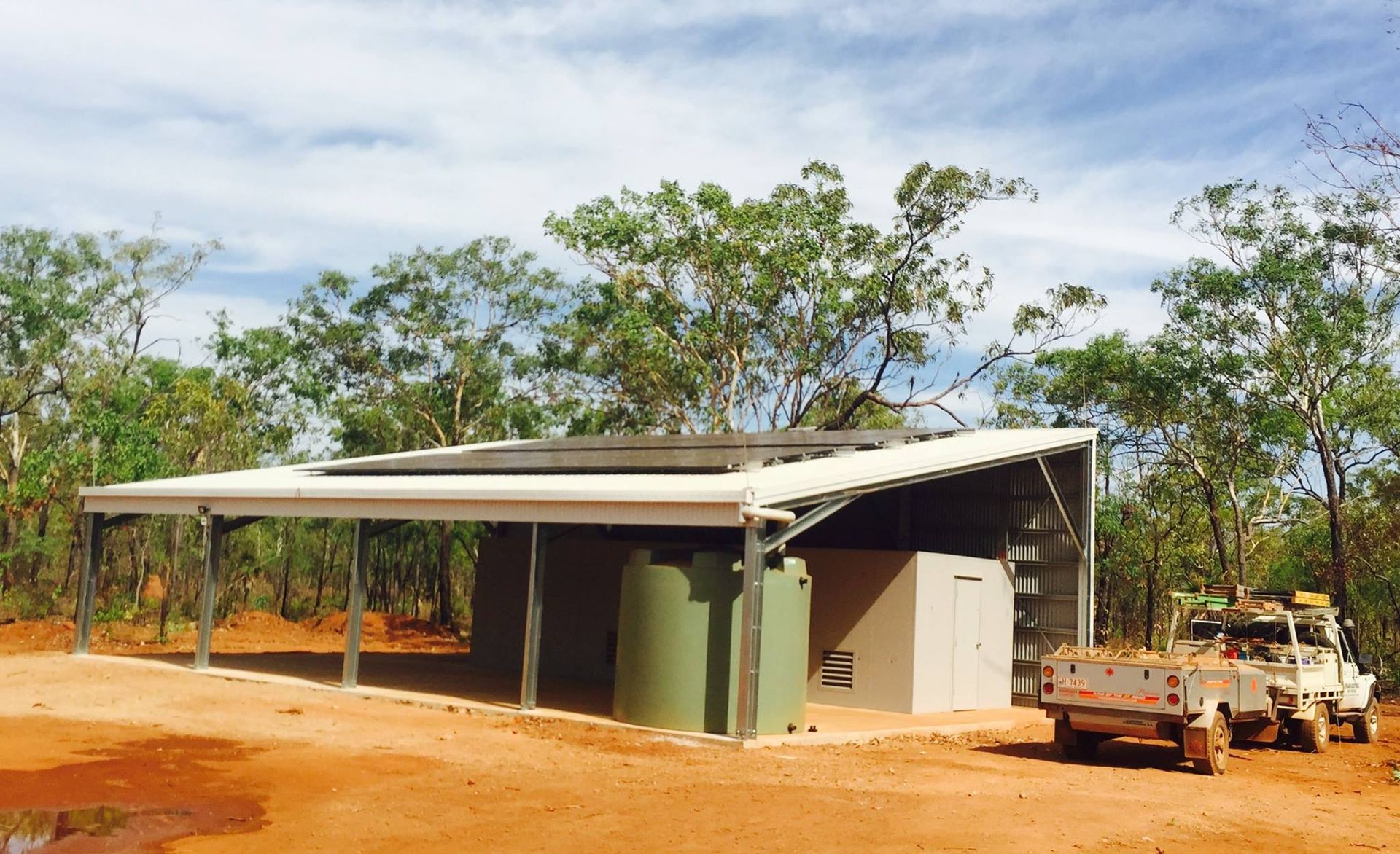 Solar Pannels On A Roof With A Green Water Tank Underneath — Inland Electrical in Humpty Doo, NT