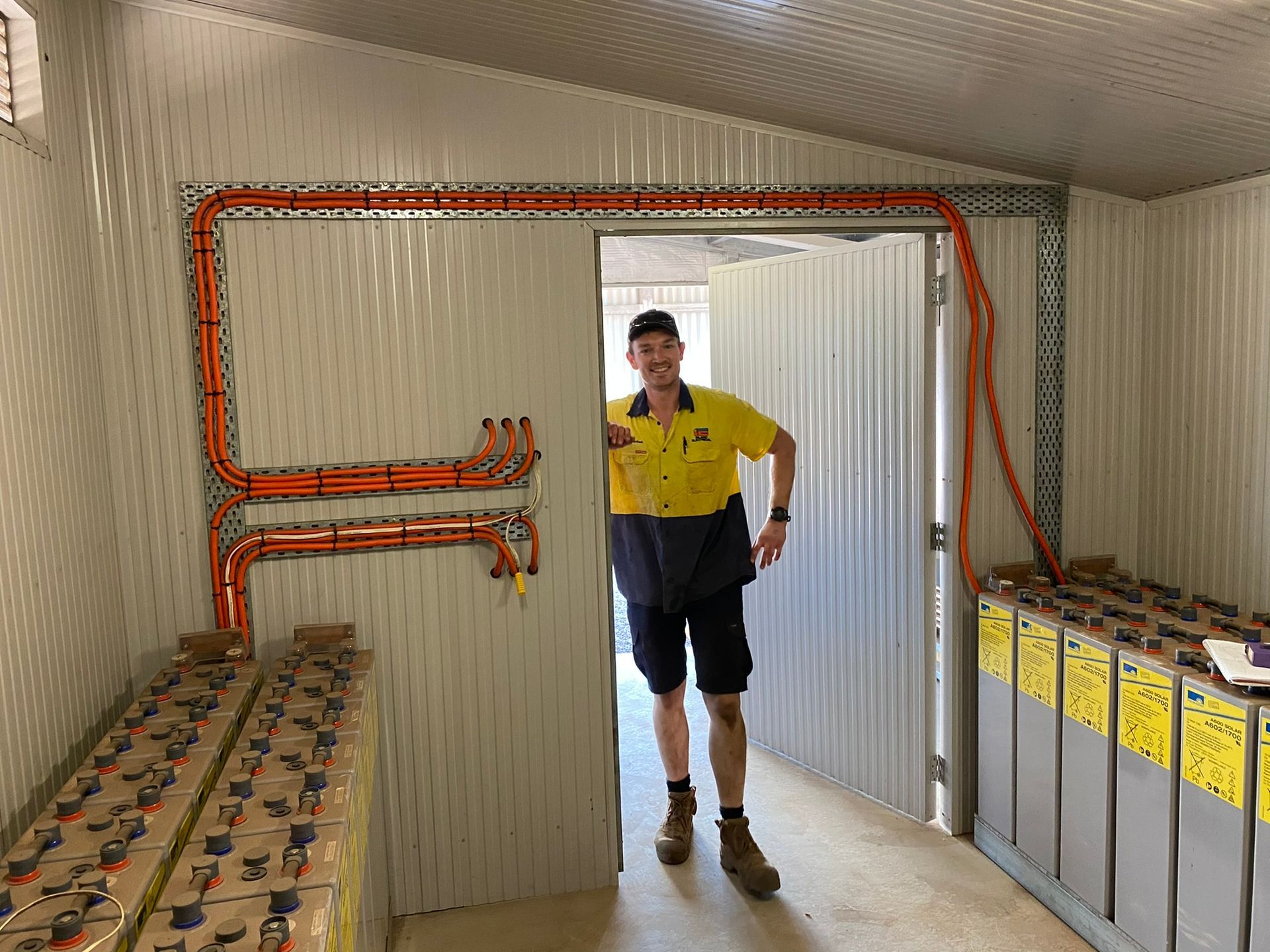 Man Standing In Doorway Next To Battery Storage — Inland Electrical in Humpty Doo, NT