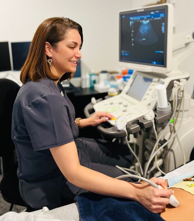A woman is sitting in front of an ultrasound machine