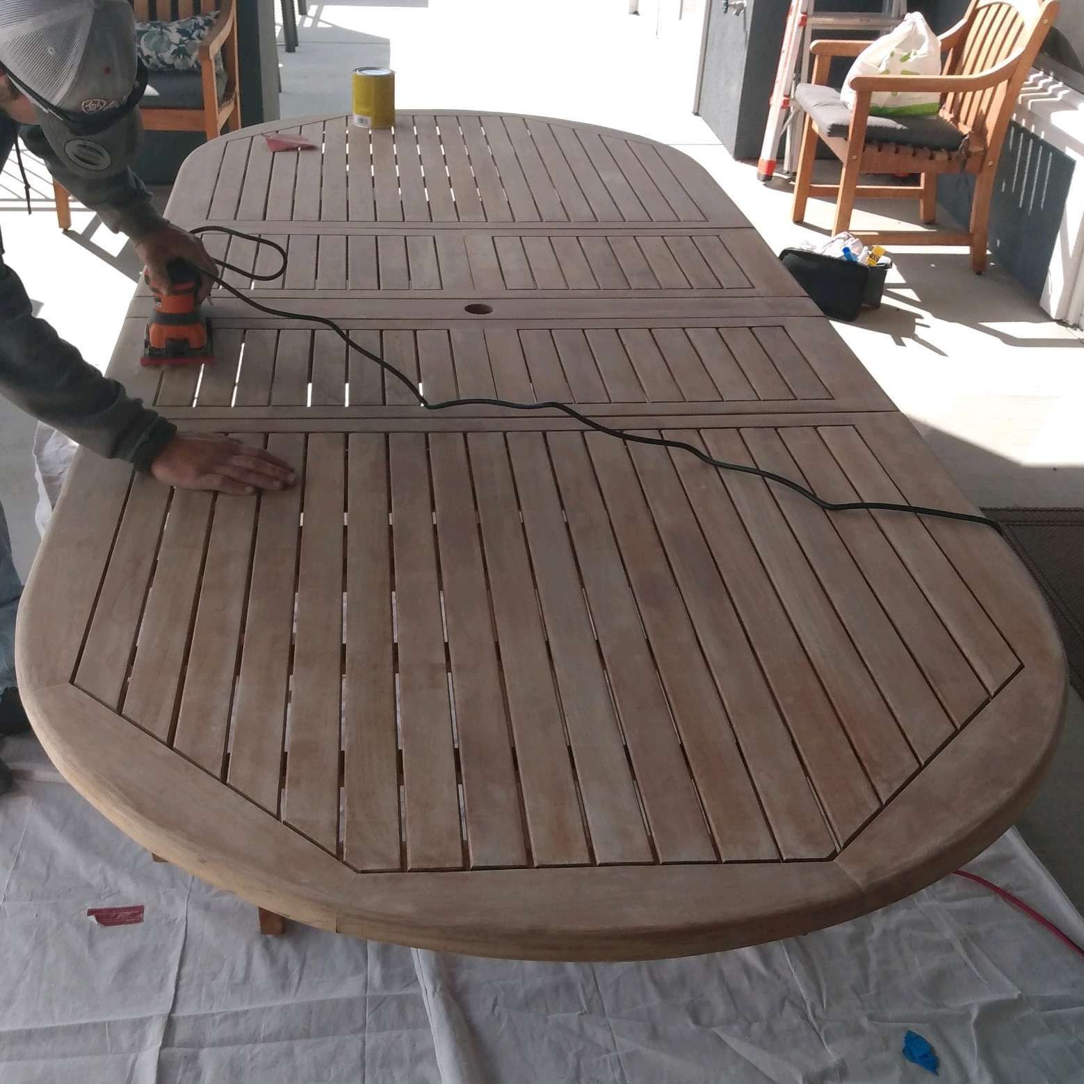 A man is sanding a wooden table with a sander