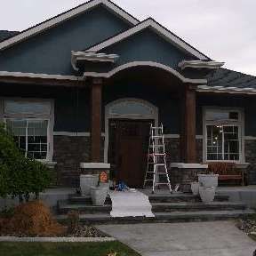 A blue house with a ladder in front of it is being painted.