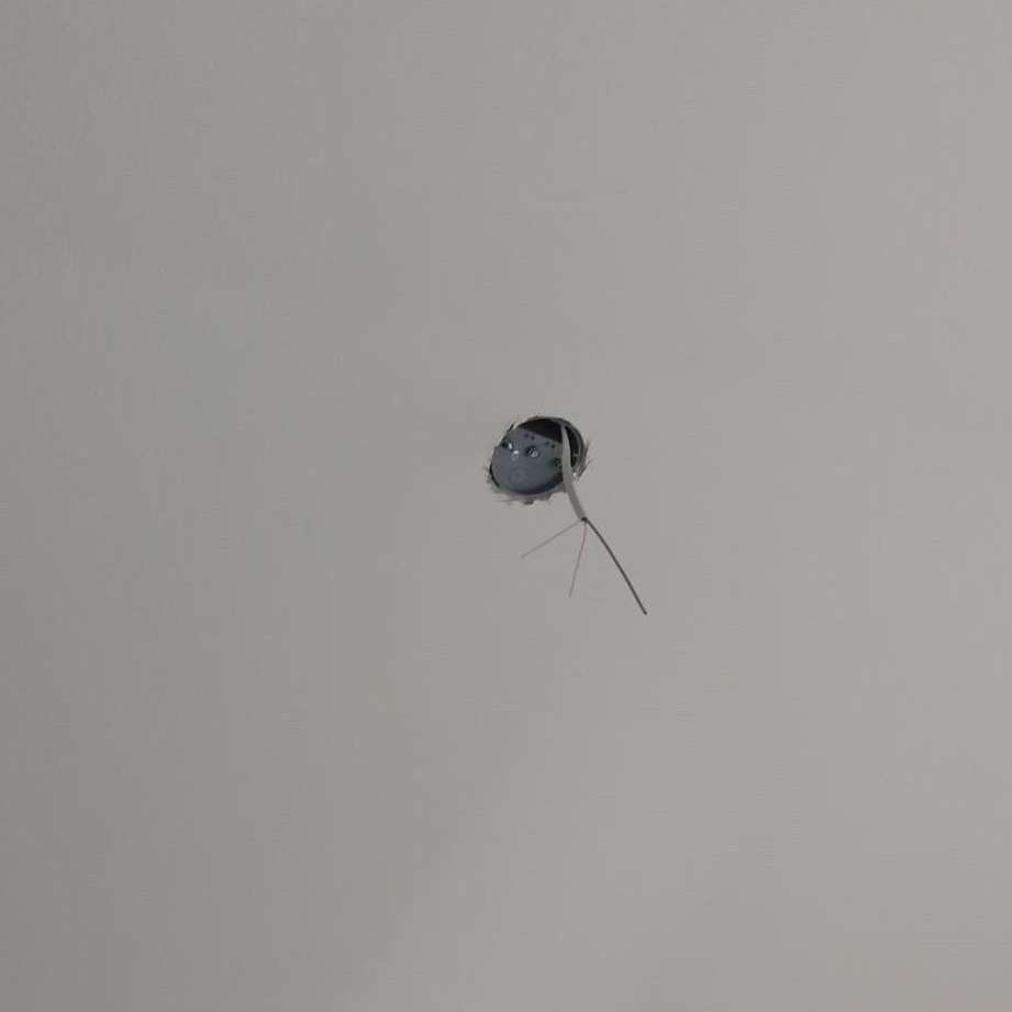 A hole in the wall with a wire sticking out of it.