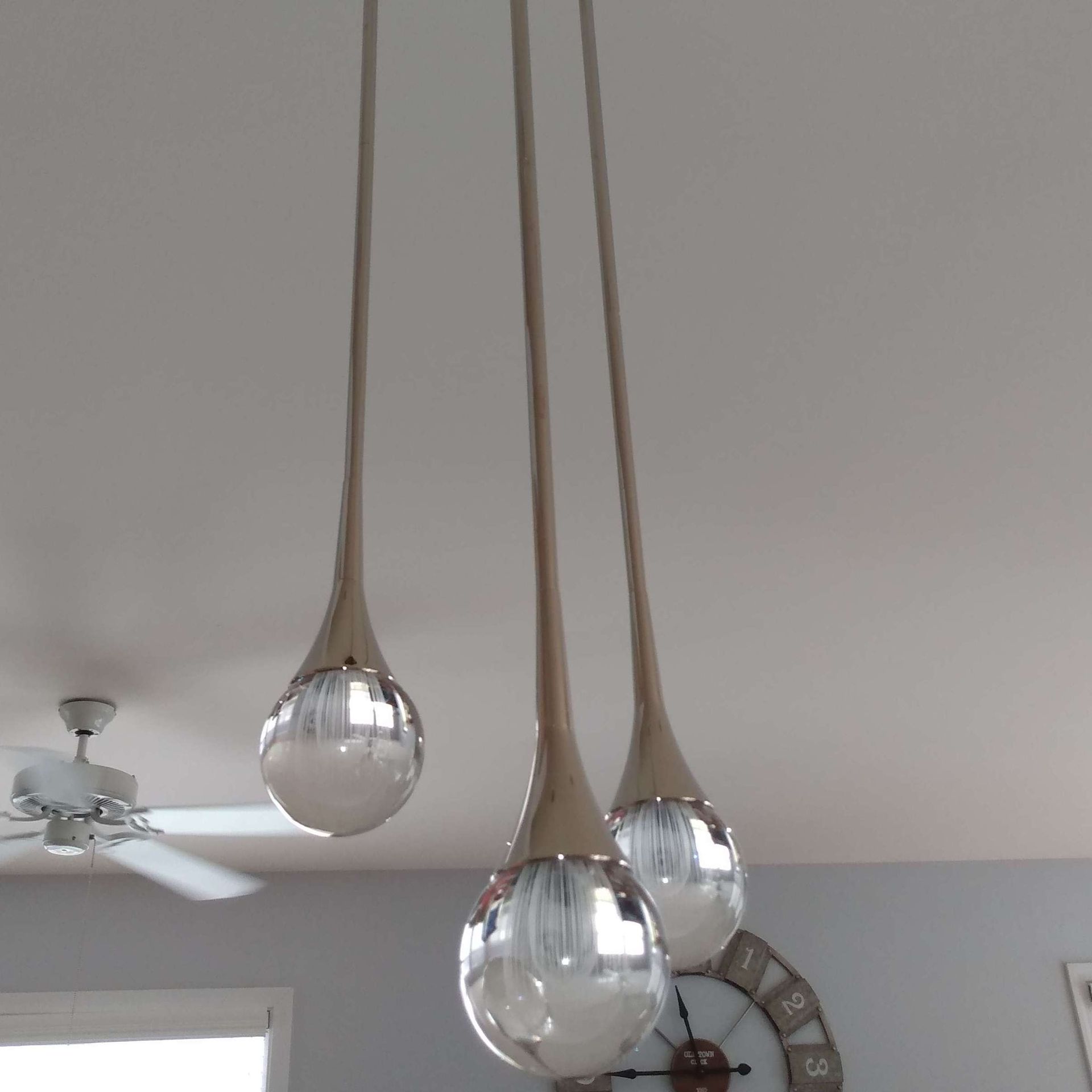 A room with a clock and three lights hanging from the ceiling