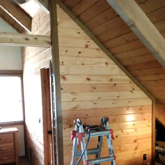 A ladder is sitting in front of a wooden wall