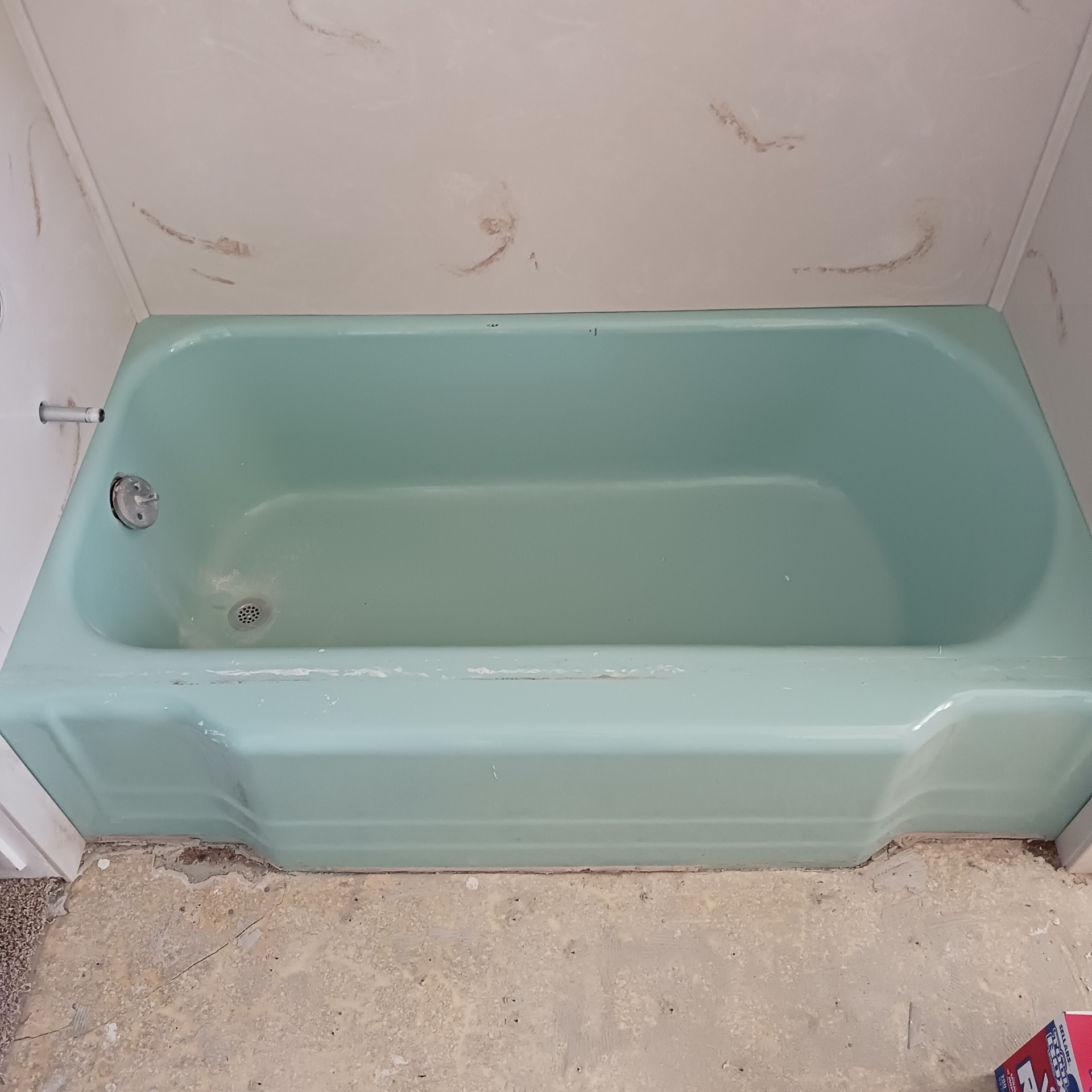 A green bathtub is sitting on the floor in a bathroom