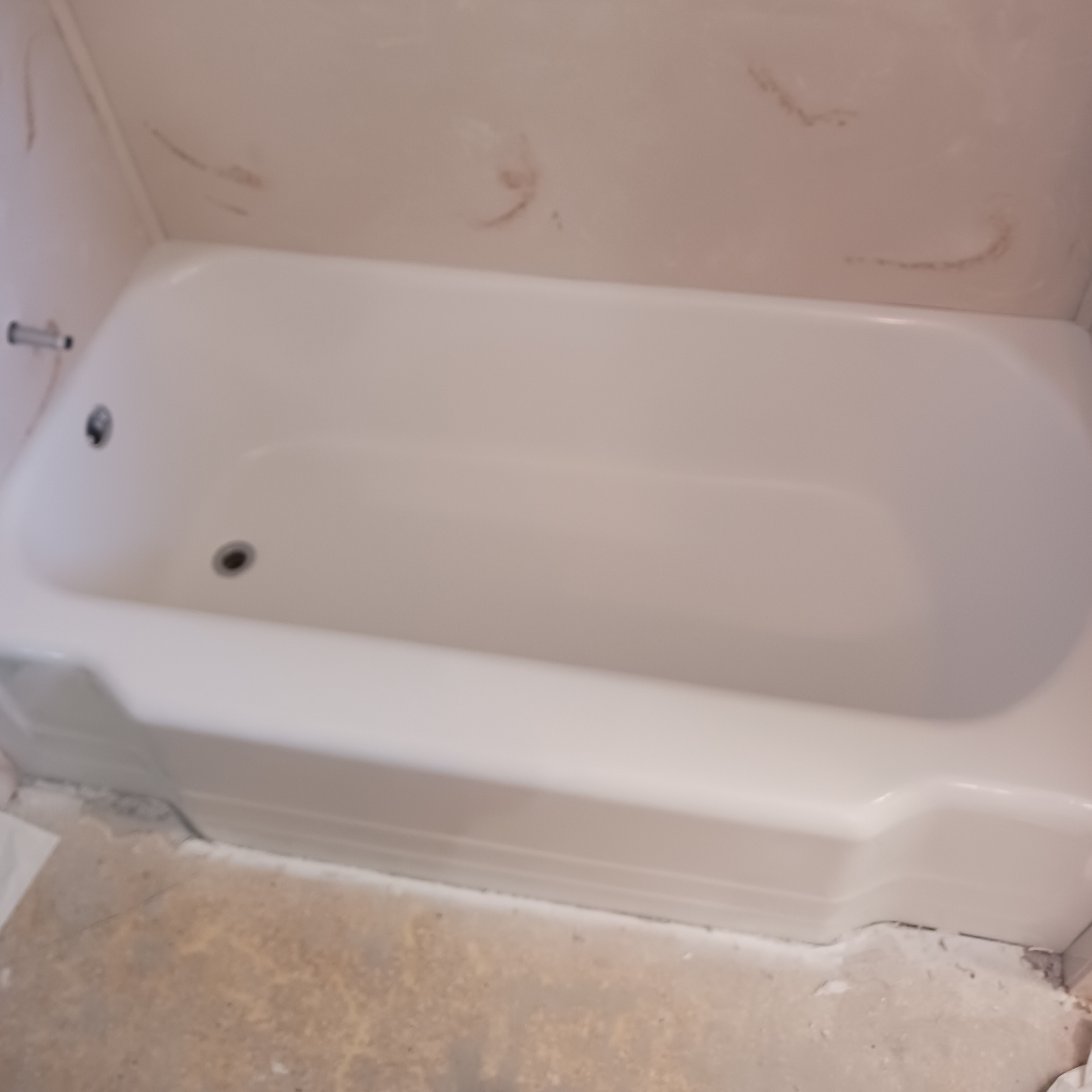 A white bathtub is sitting on the floor in a bathroom.