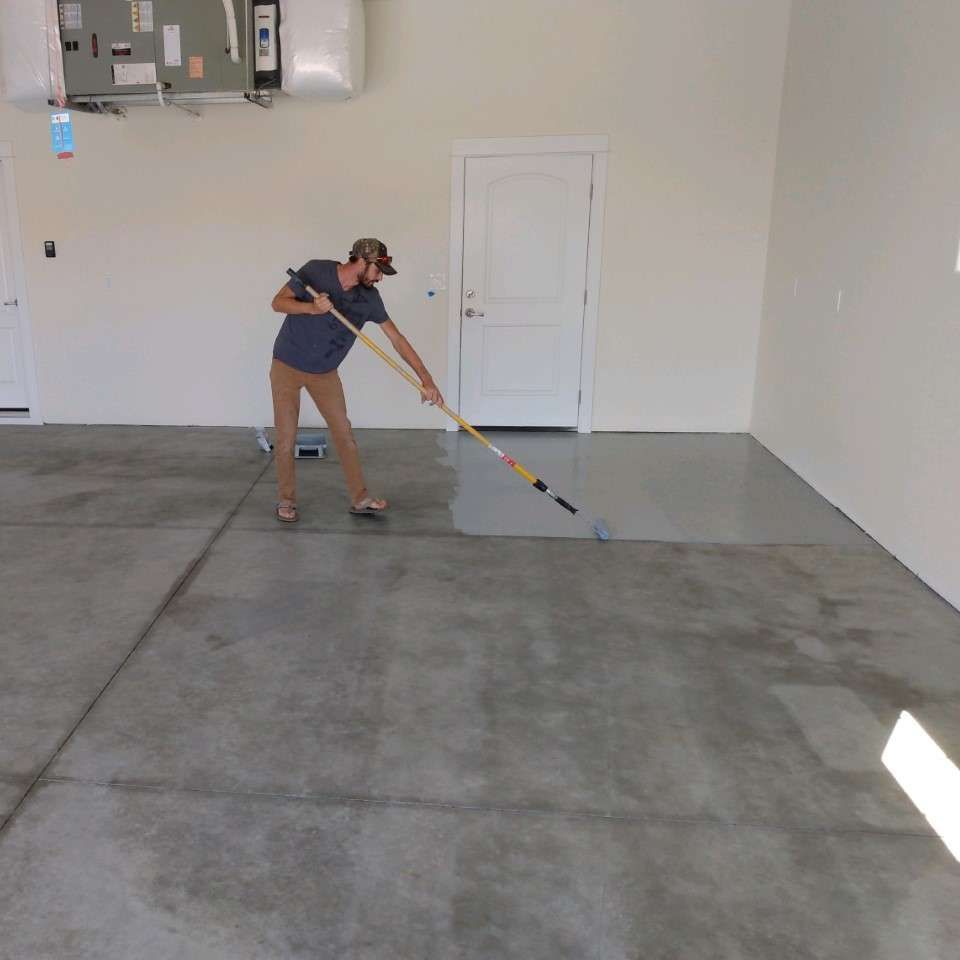 A man is painting a concrete floor in a garage