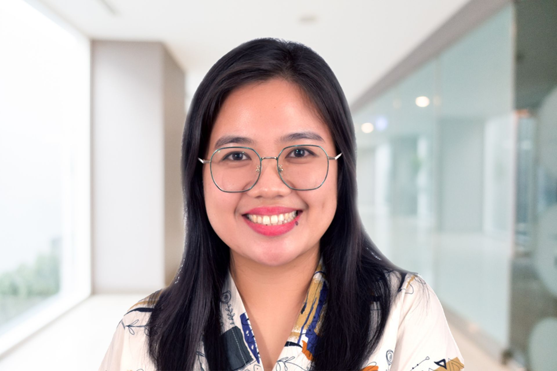 Woman with glasses smiles in an office setting.