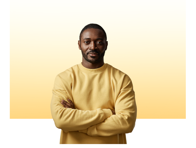 Man with crossed arms wearing a yellow sweater against a yellow gradient backdrop.