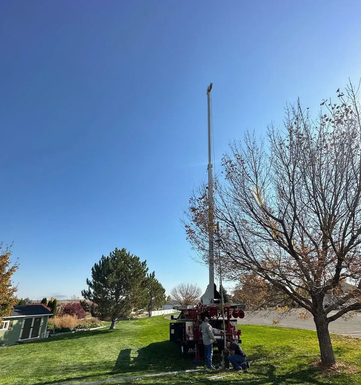 A man is standing next to a large machine in a grassy field.