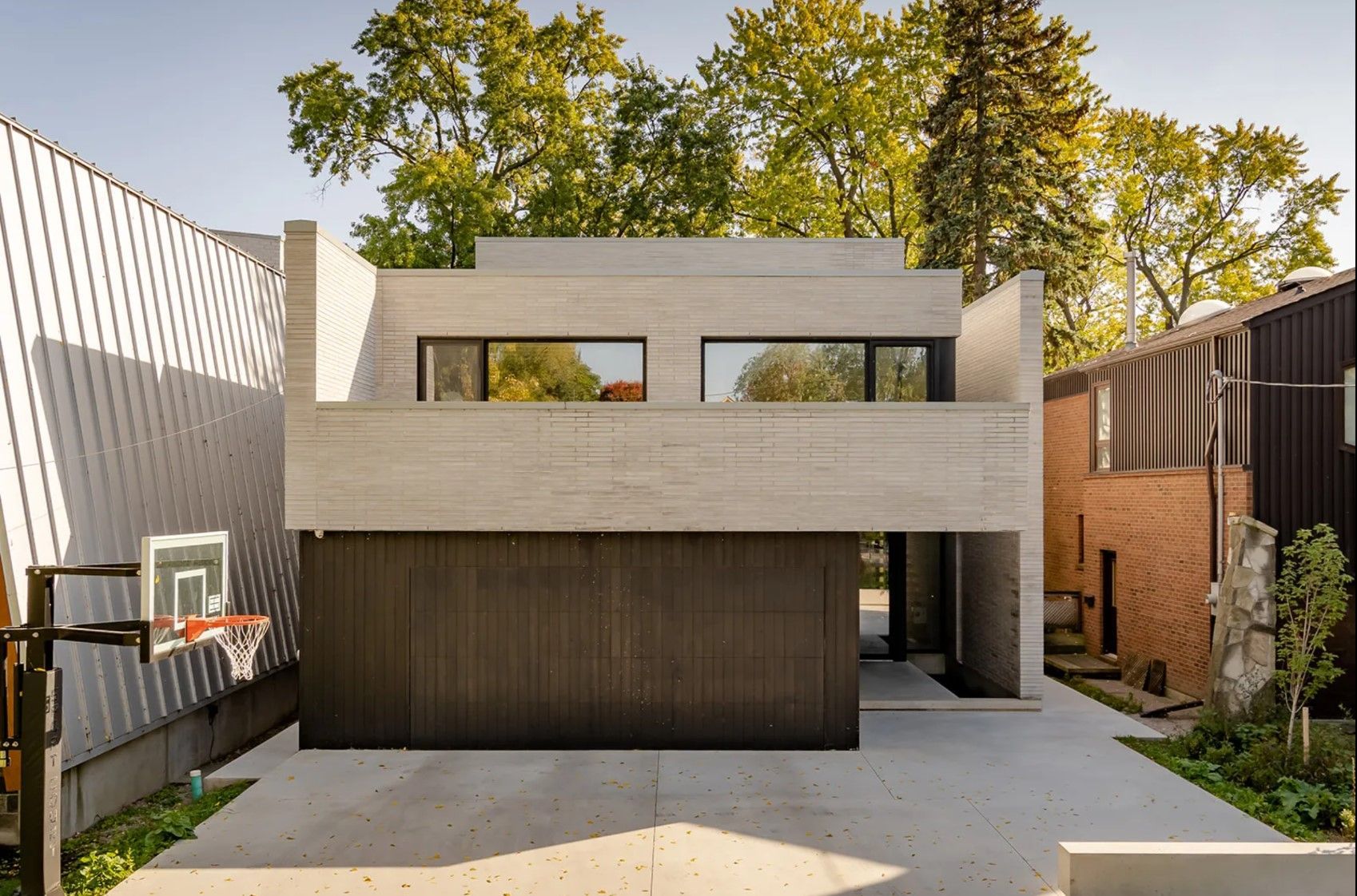 A modern house with a basketball hoop in front of it.