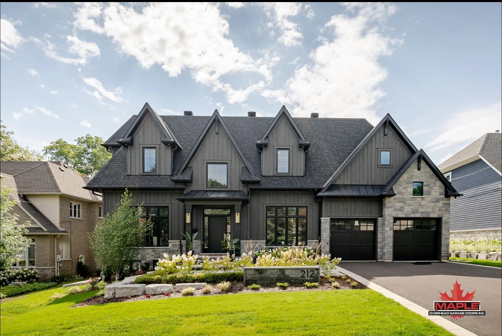 A large house with a black roof is sitting on top of a lush green lawn.