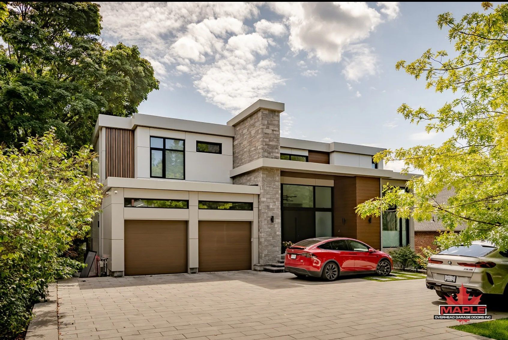 A red car is parked in front of a modern house