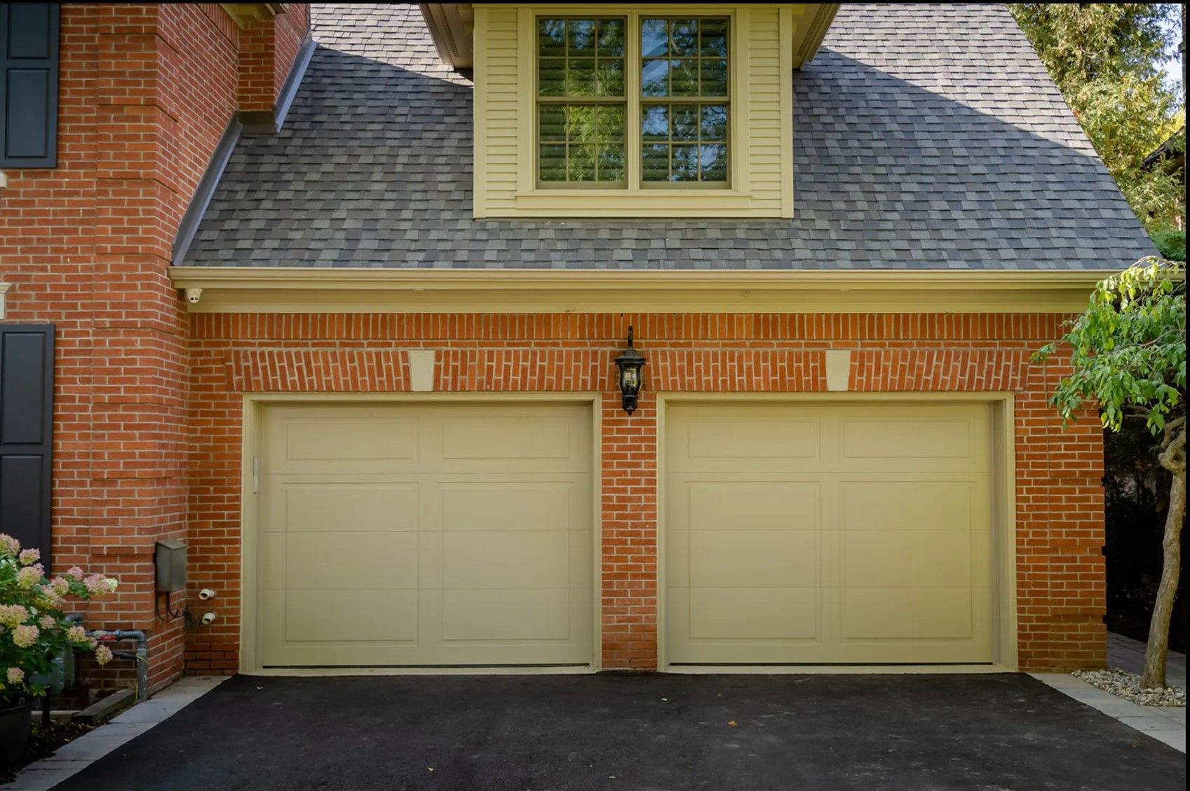 A brick house with two garage doors and a window.