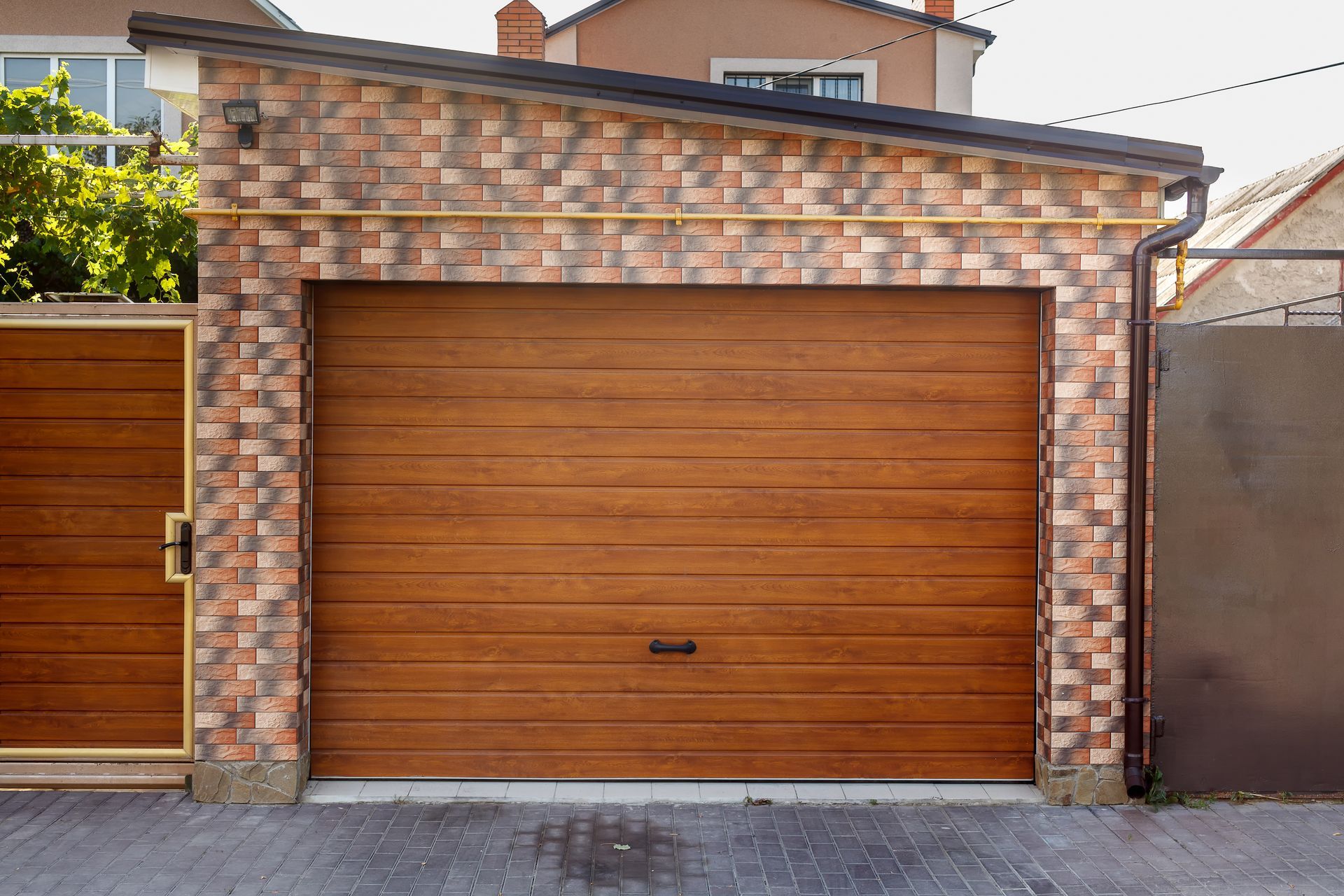 A garage with a wooden door and a brick wall.