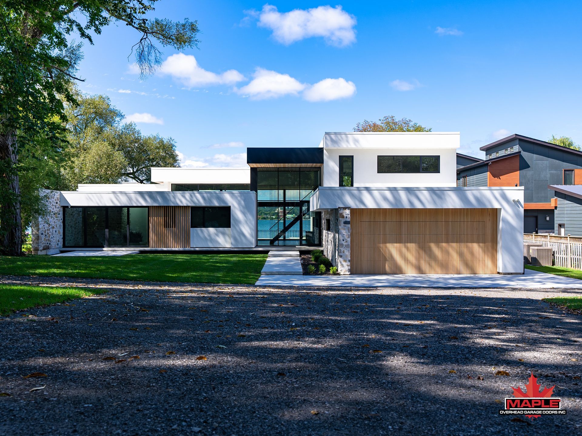 A modern white house with a wooden garage door is sitting on top of a lush green lawn.