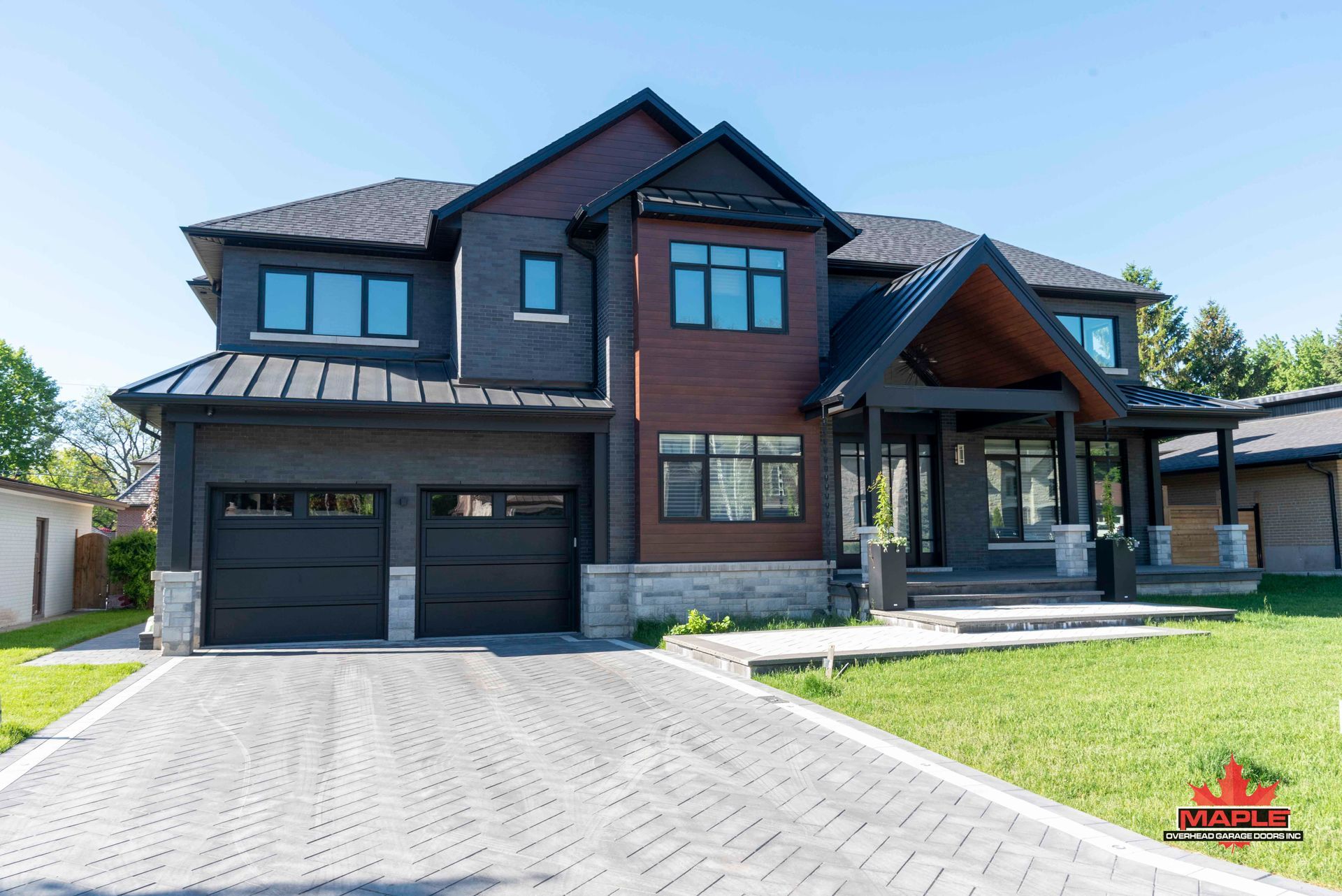 A large house with a black garage door is sitting on top of a lush green lawn.