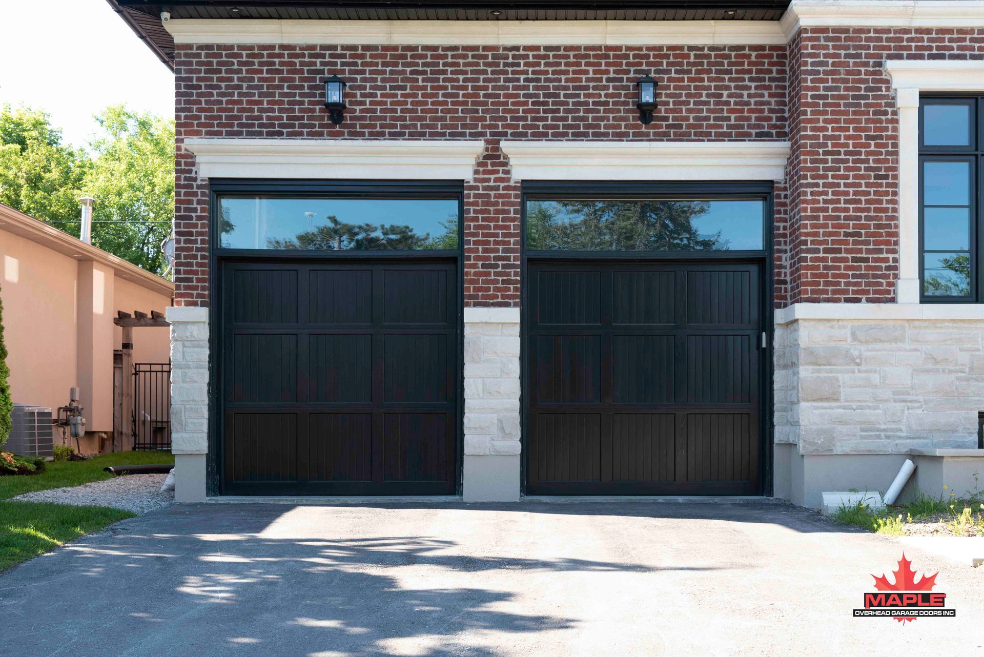 A brick house with two black garage doors and a driveway