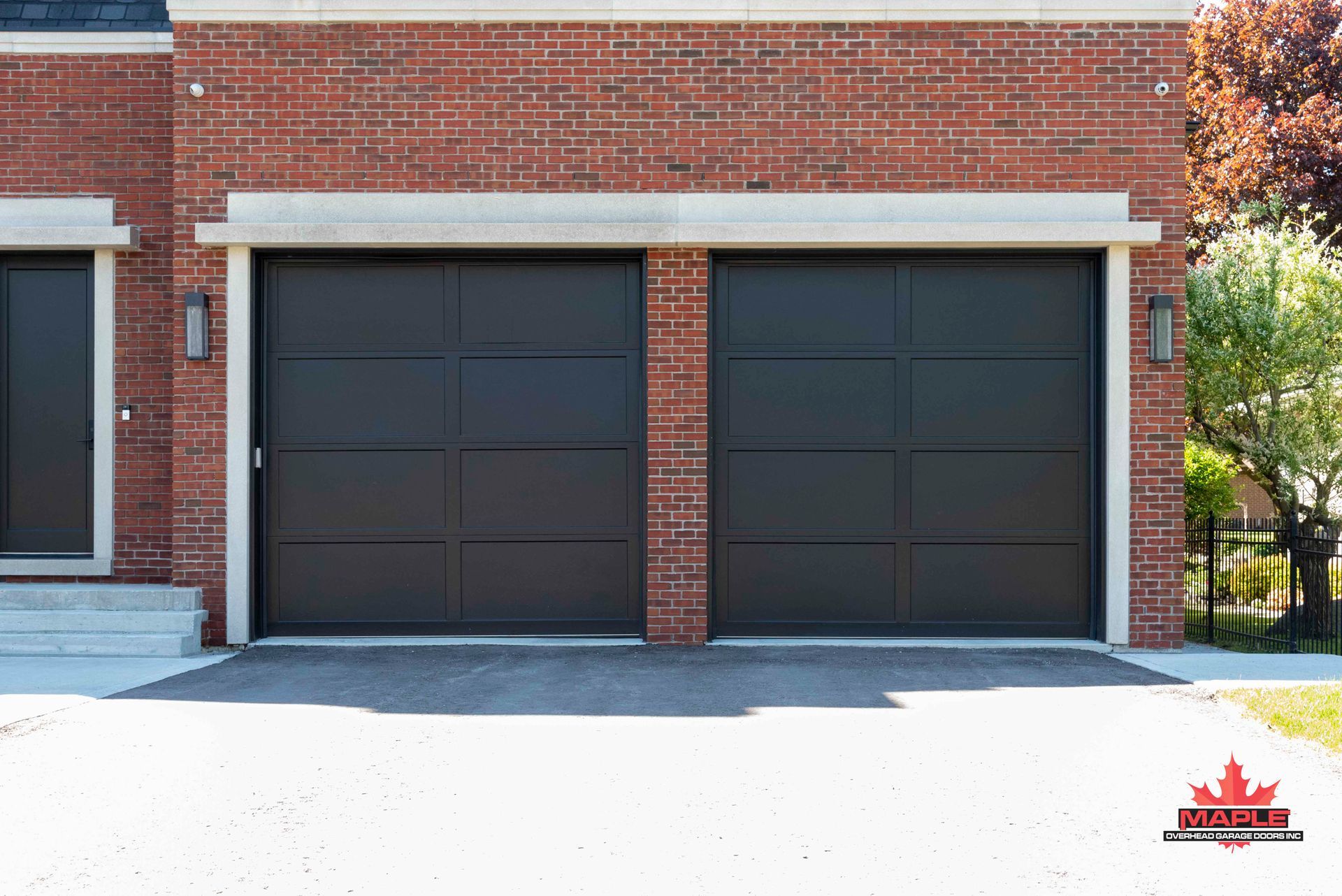 A brick house with two black garage doors and a driveway.