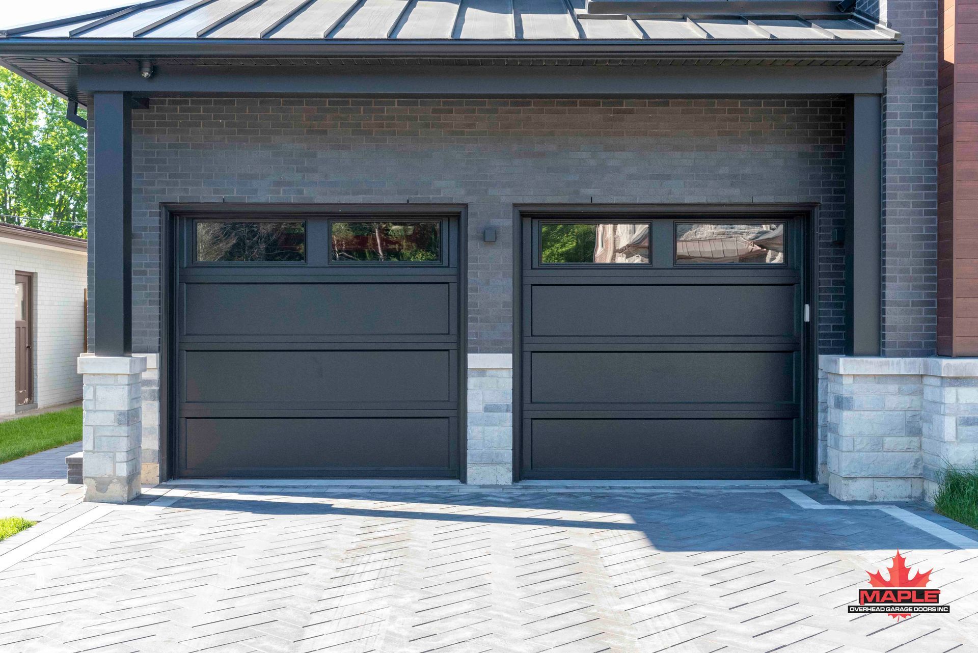 A black garage door is sitting in front of a brick house.
