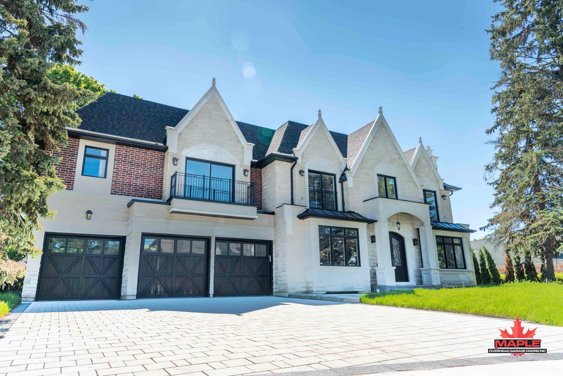 A large white house with black garage doors is for sale.