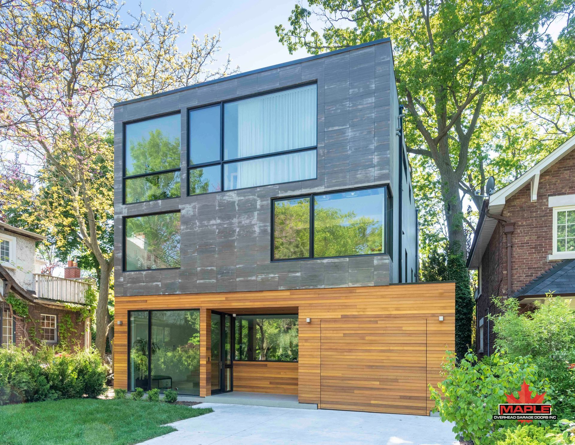 A modern house with a lot of windows and a brick house in the background