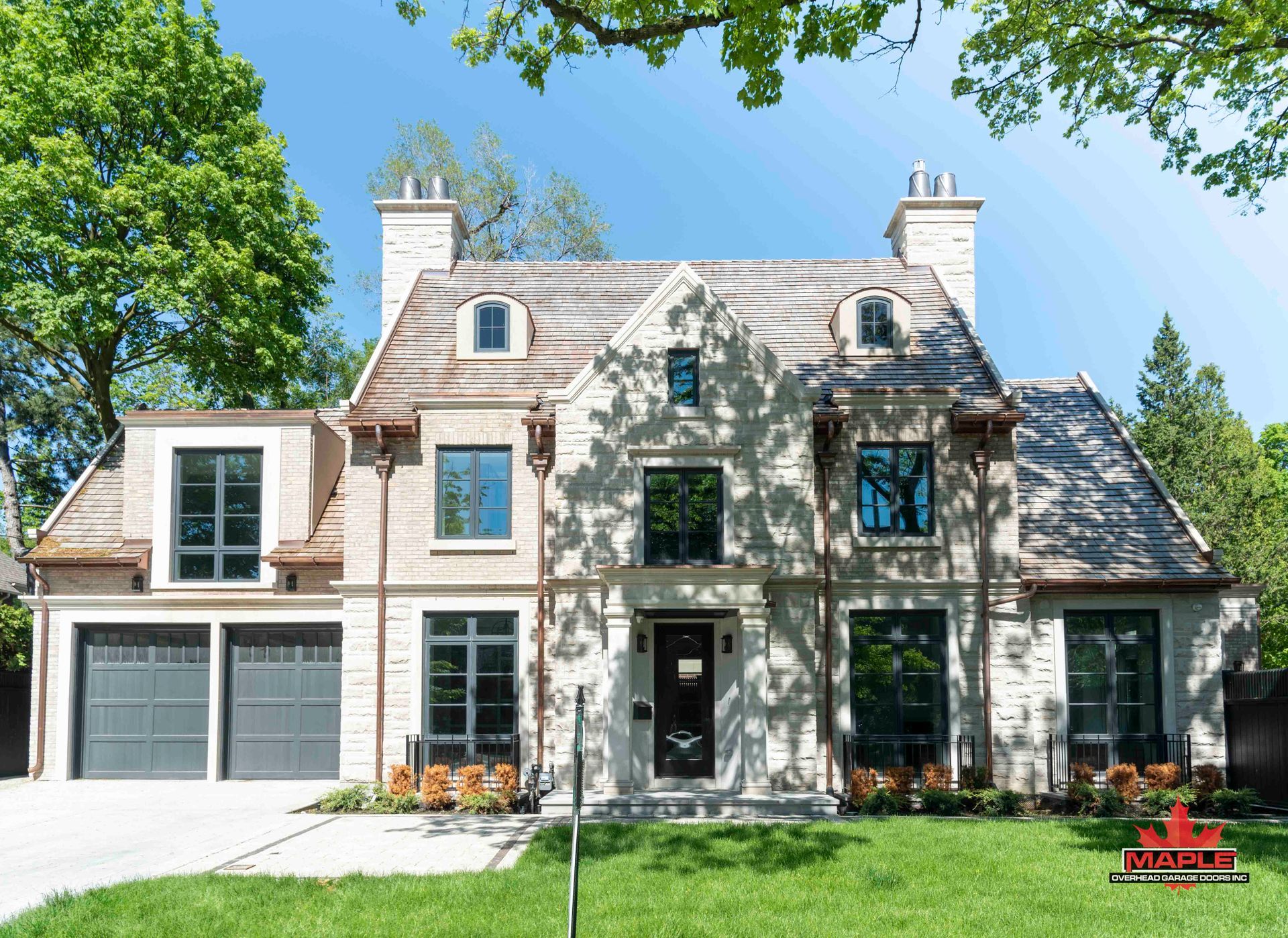 A large white house with a gray garage door is sitting on top of a lush green lawn.
