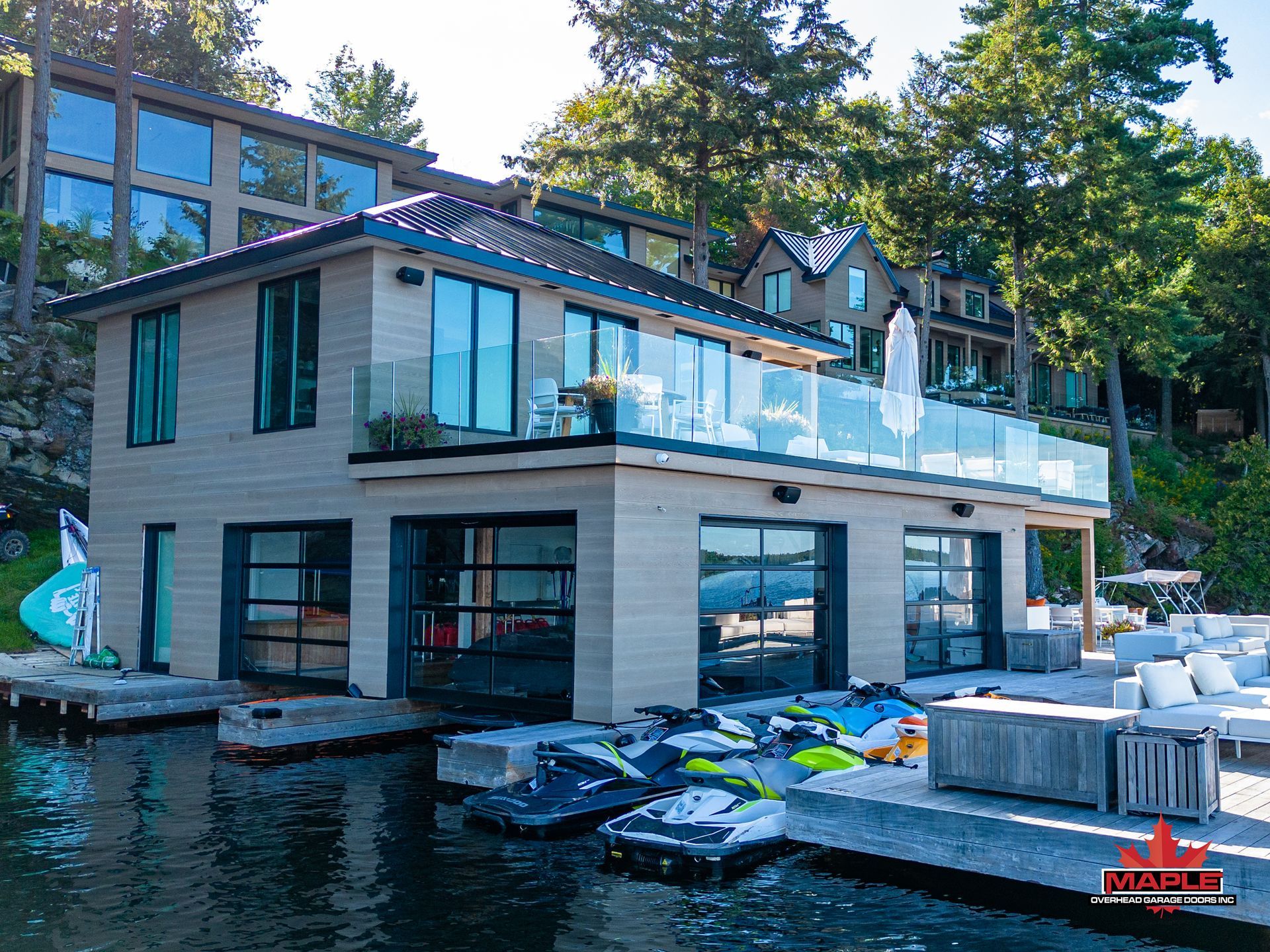 A large house with a lot of windows sits next to a body of water