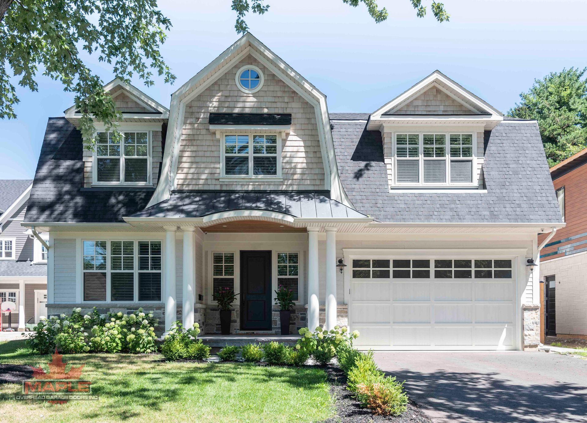 A large white house with a black roof and a white garage door