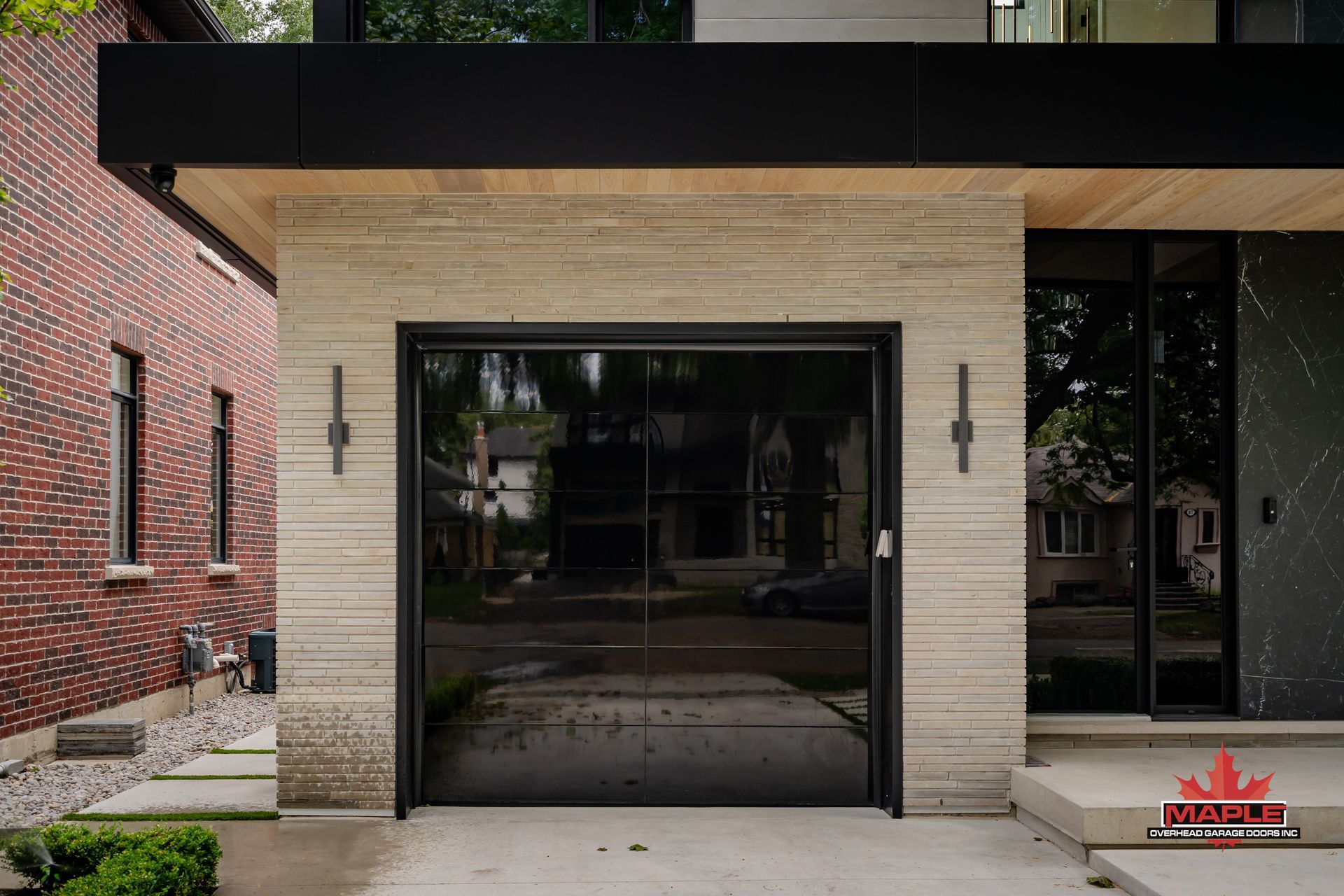 A modern house with a black garage door and a brick wall.