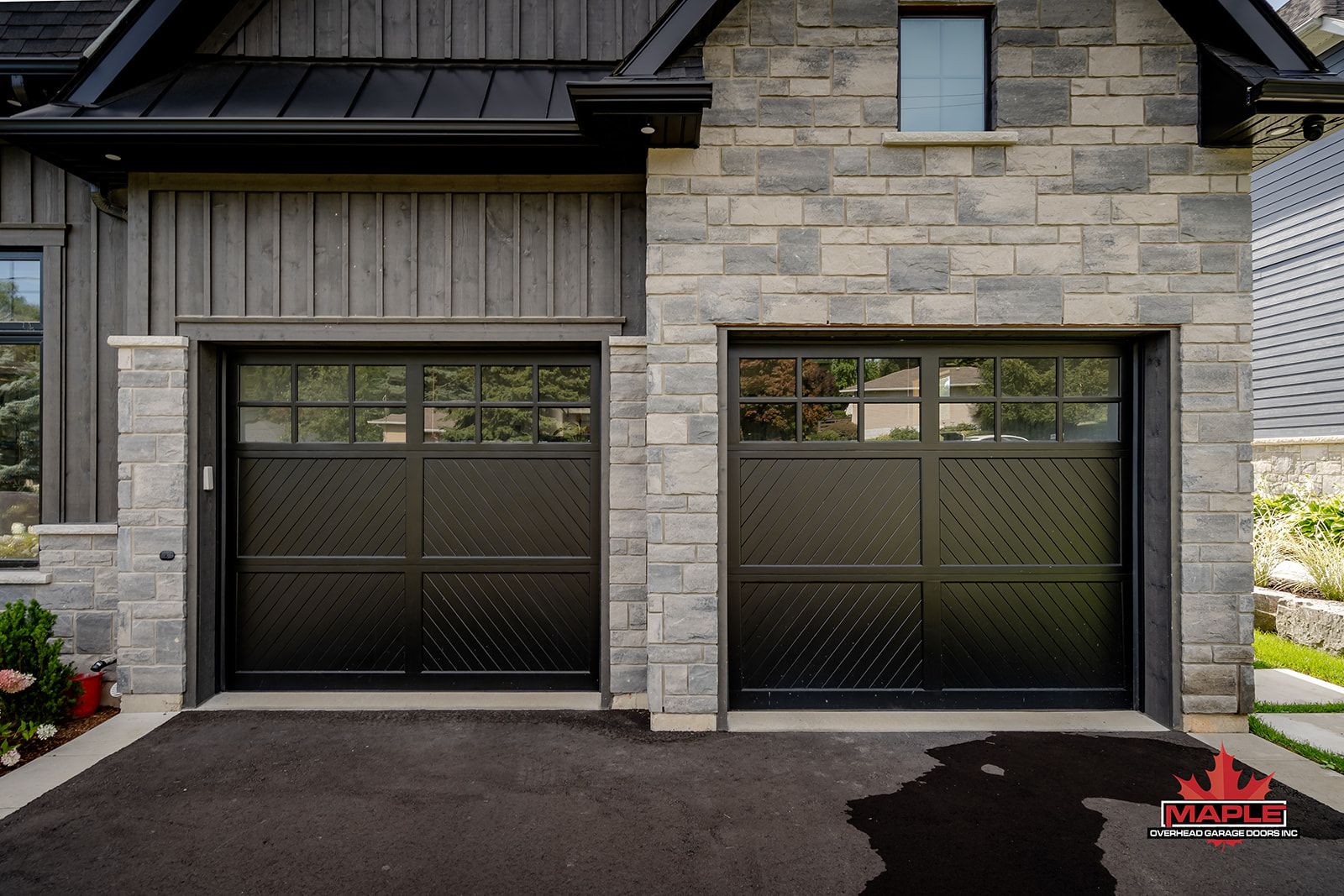 A house with a black garage door and a black driveway