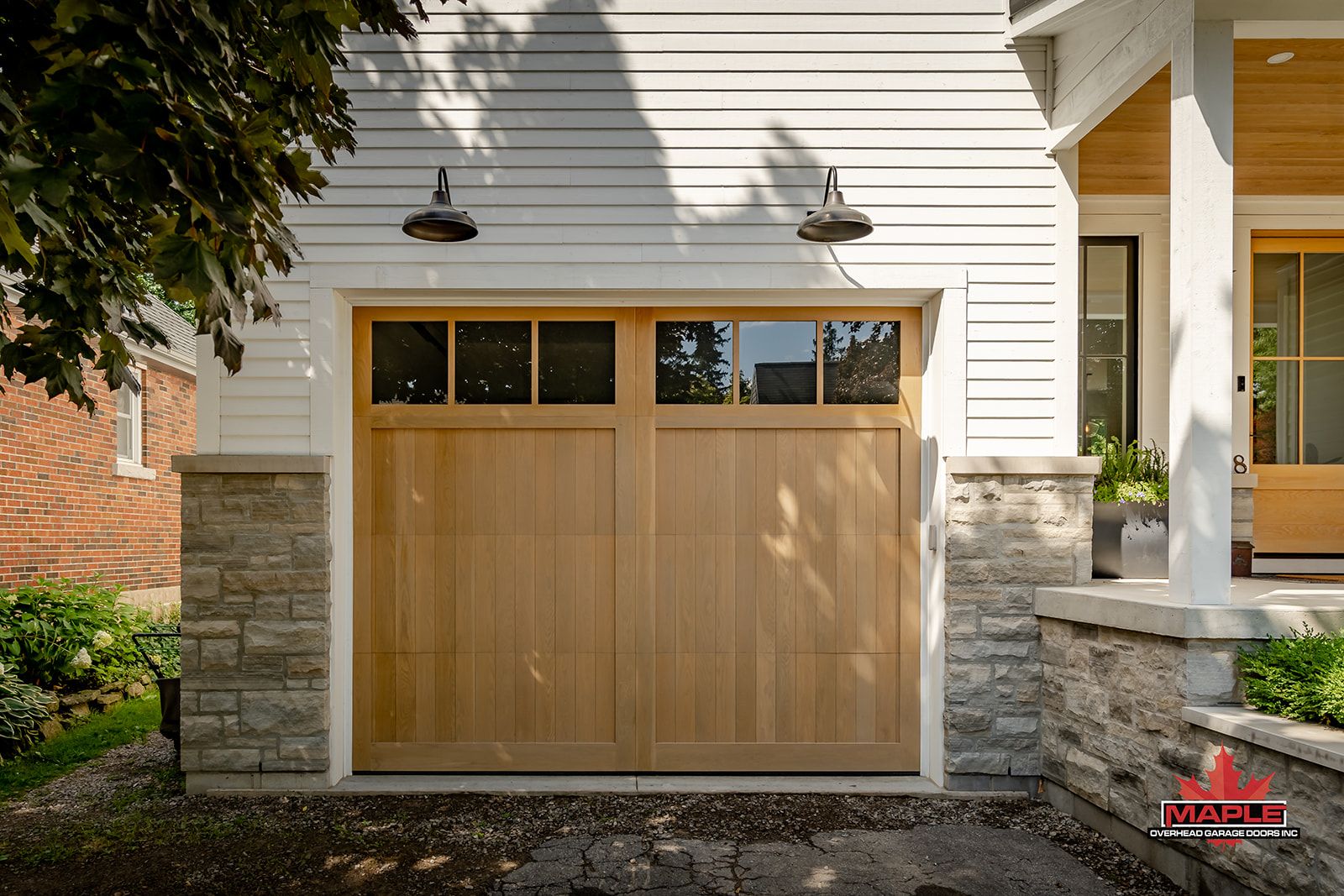 A wooden garage door is sitting in front of a white house.